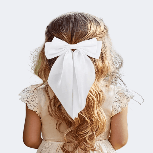 Person with long blonde hair wearing a large white bow, wearing a beige dress on a light background
