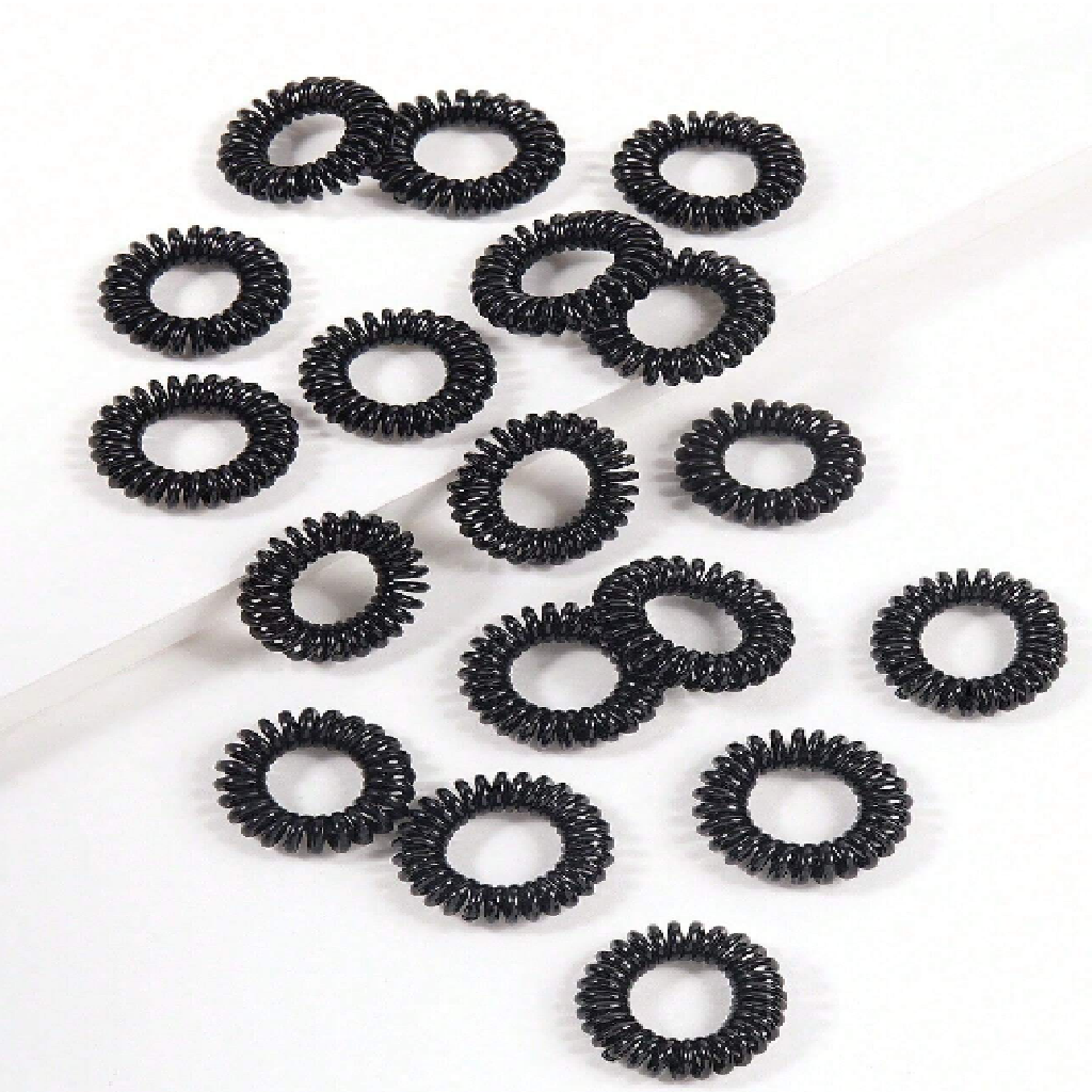 Multiple black hair ties arranged on a white background