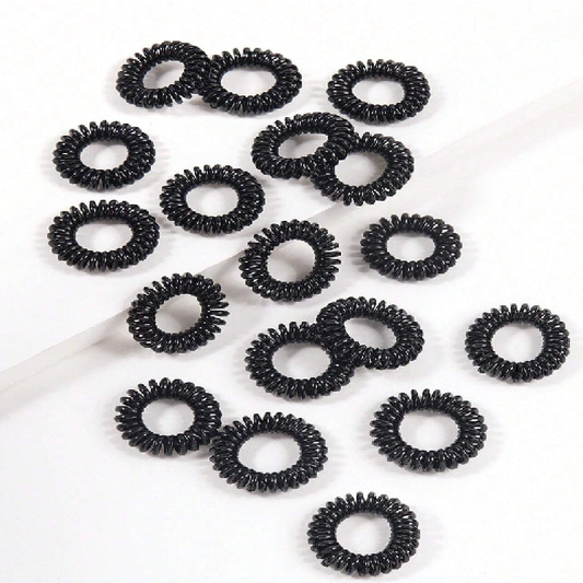 Multiple black hair ties arranged on a white background