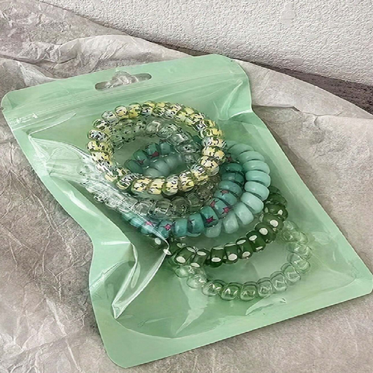 Set of colorful beaded bracelets on a green plastic bag with a textured surface background.