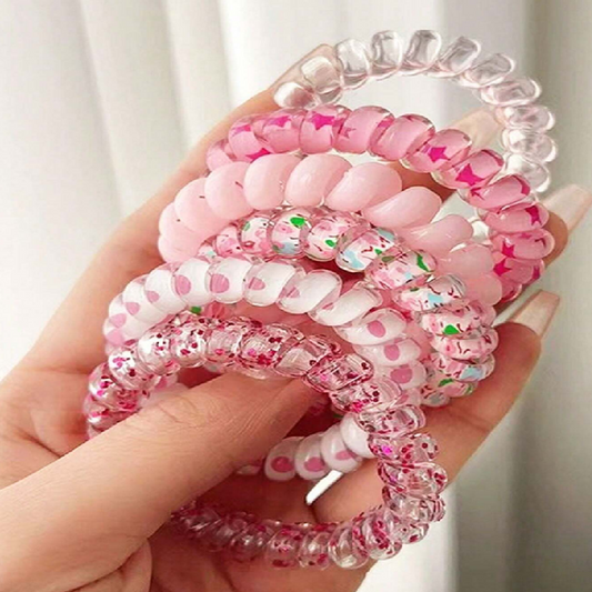 Hand holding pink and clear beaded hair ties against a neutral background