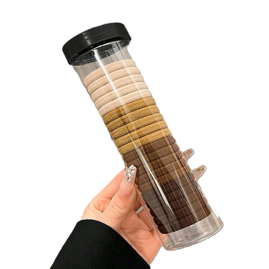Hand holding a cylindrical container with layered sand resembling a mountain.