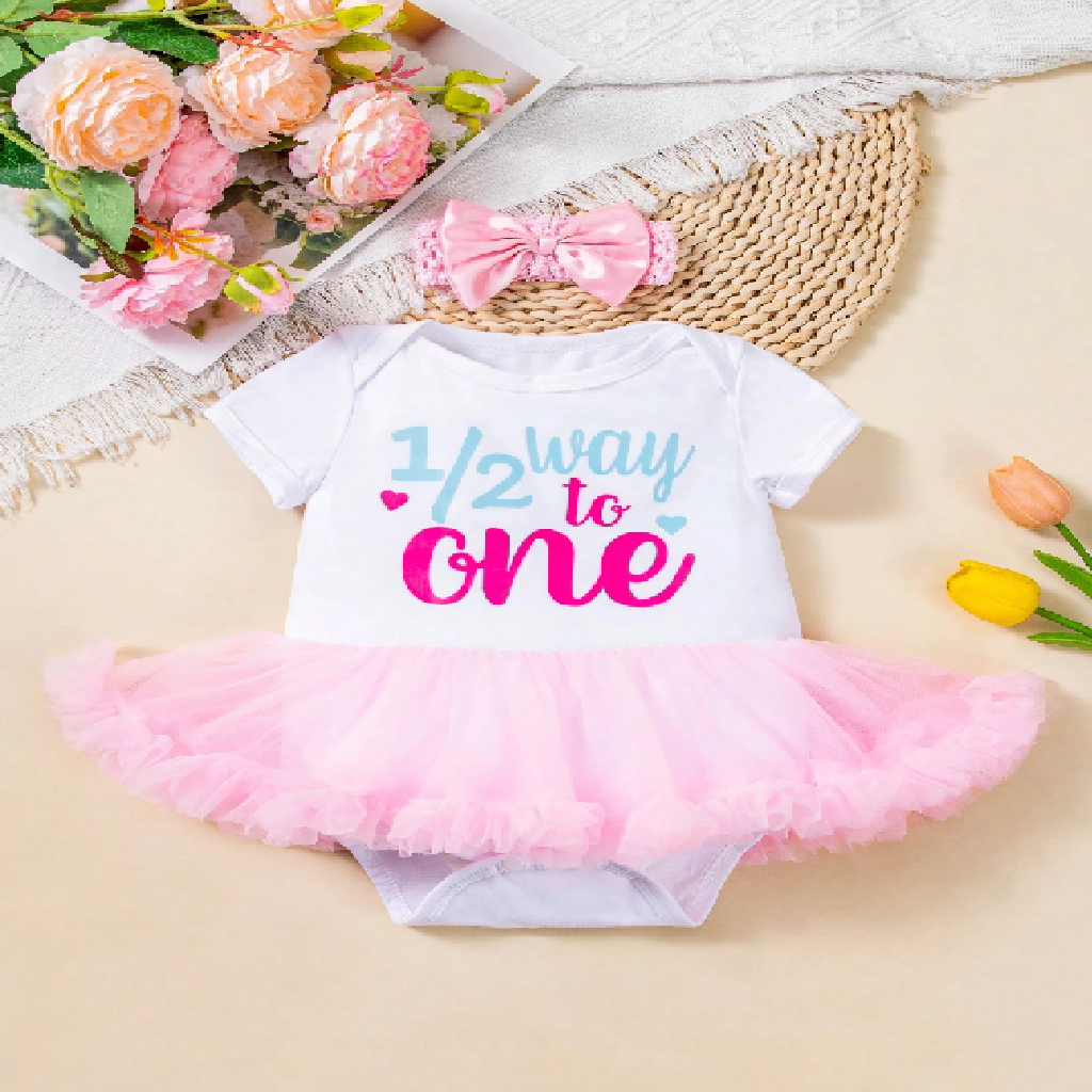 Baby outfit with '1/2 way to one' text and pink tutu on a light background with flowers and a hat.