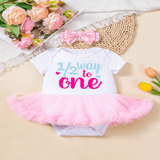 Baby onesie with pink tutu and floral decorations on a light background