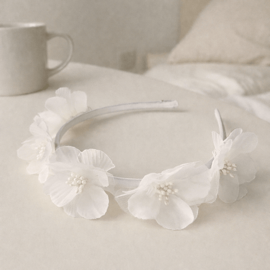 White floral headband on a light surface with a blurred background