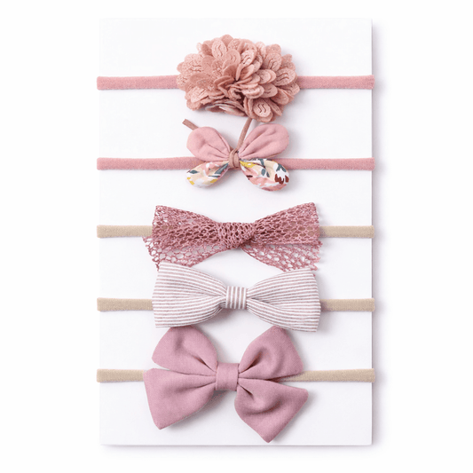 Set of pink hair accessories including bows and a floral headband on a white background