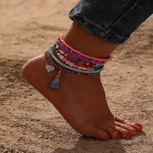 Ankle with colorful beaded anklets on a sandy background
