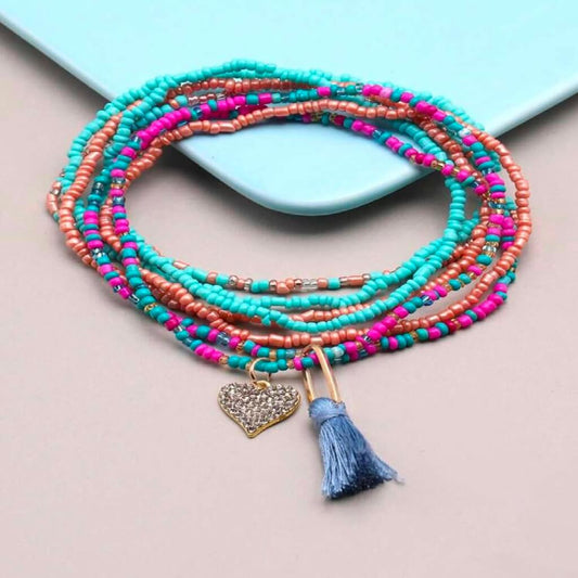 Colorful beaded anklets on a foot with a plain background
