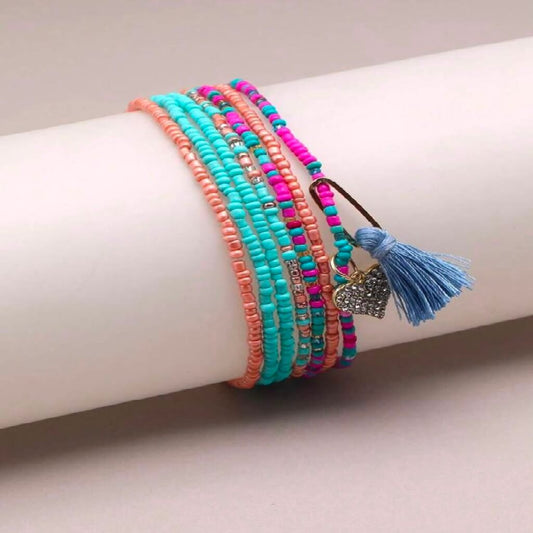 Colorful beaded anklets on a foot with a plain background