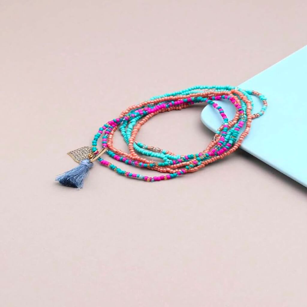 Colorful beaded anklets on a foot with a plain background