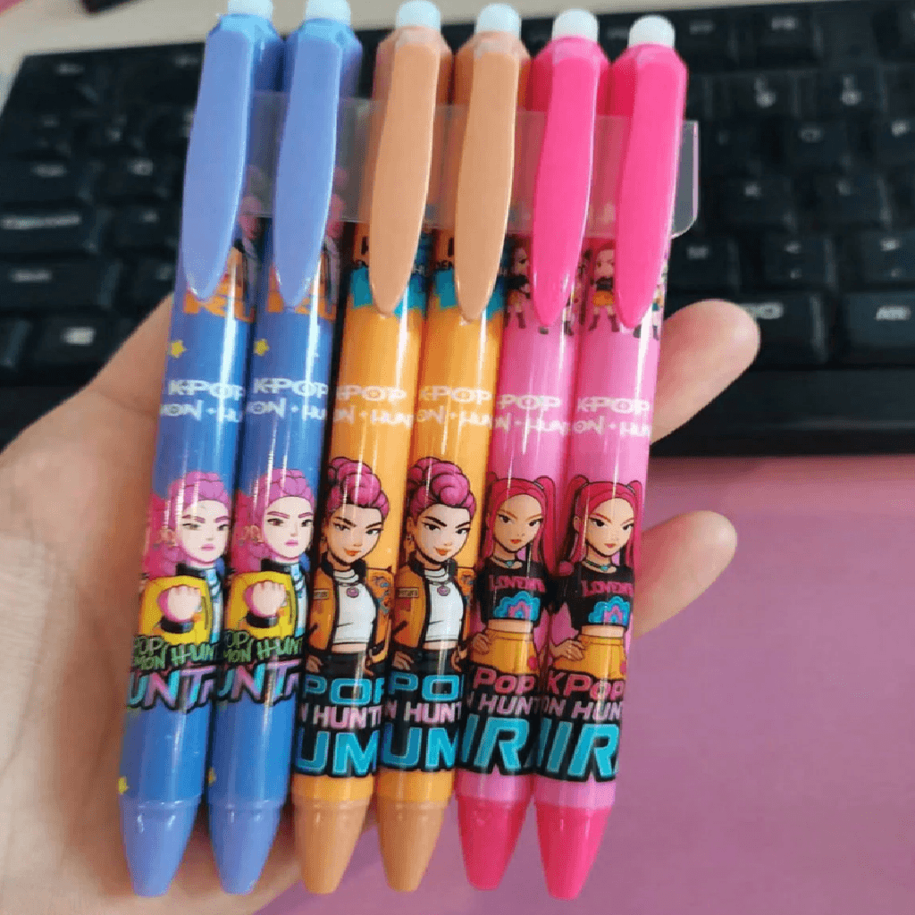 Five colorful pens with cartoon character design held in front of a keyboard.