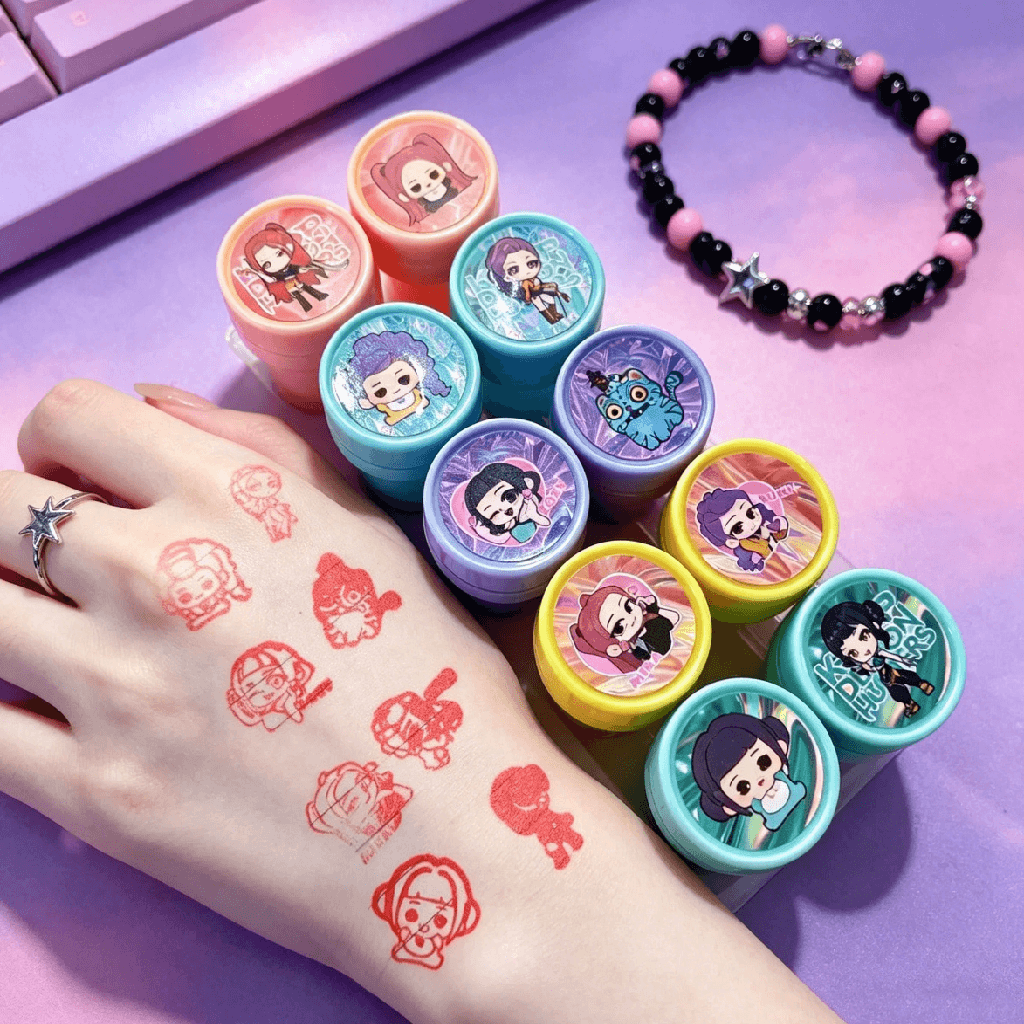 Set of cartoon-themed tattoo stamps with colorful designs on a hand and bracelet on a purple surface.