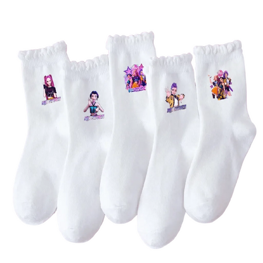 Five white crew socks with ruffled cuffs are arranged in a fan shape on a solid pink background. Each sock features a small colorful printed graphic of a female cartoon character with text below it.