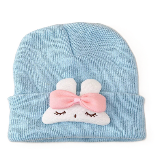 Light blue knit baby hat with a cartoon face and pink bow on a white background