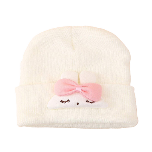 White beanie with a pink bow and cat face design on a white background