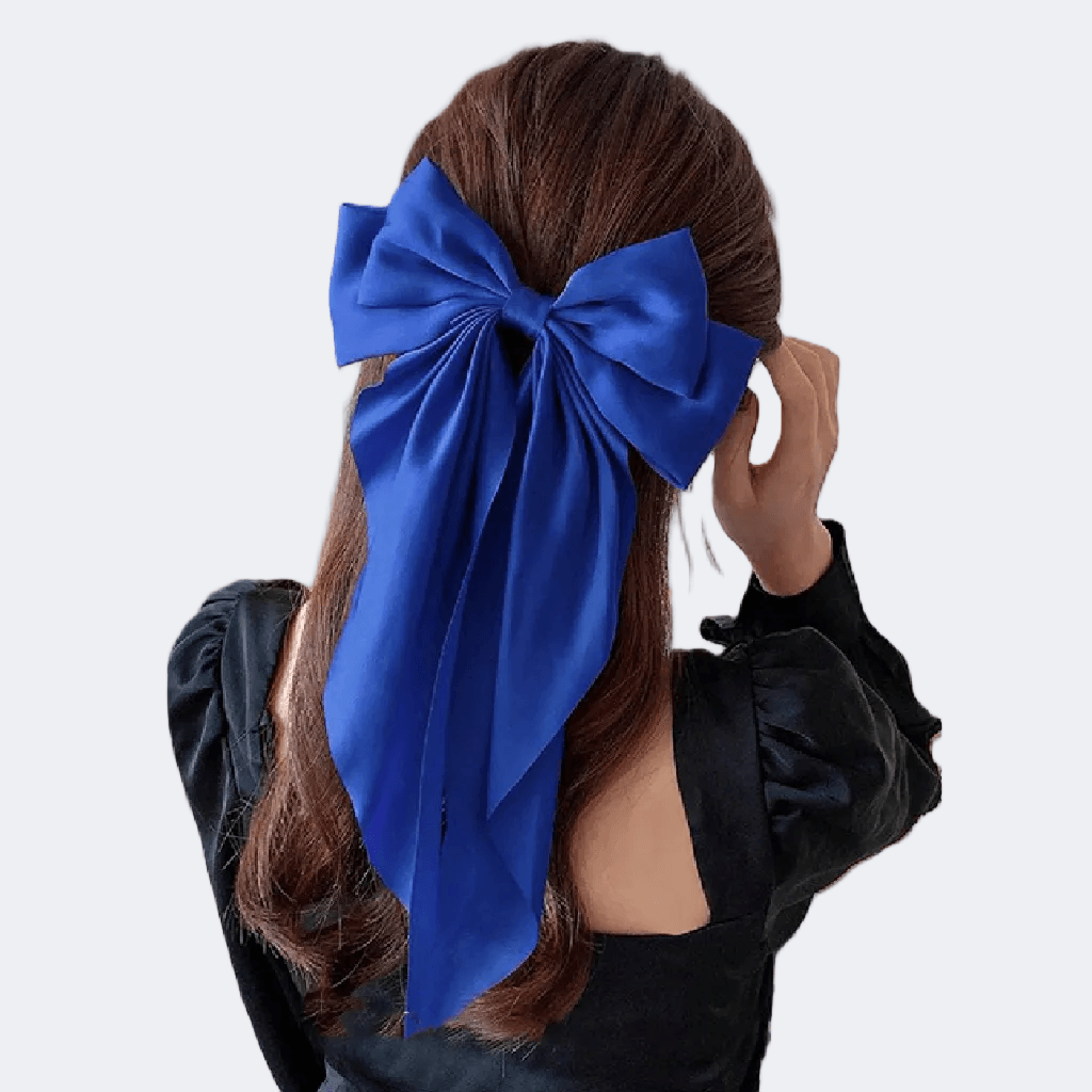 Person with long dark hair wearing a large blue bow in the back on a white background