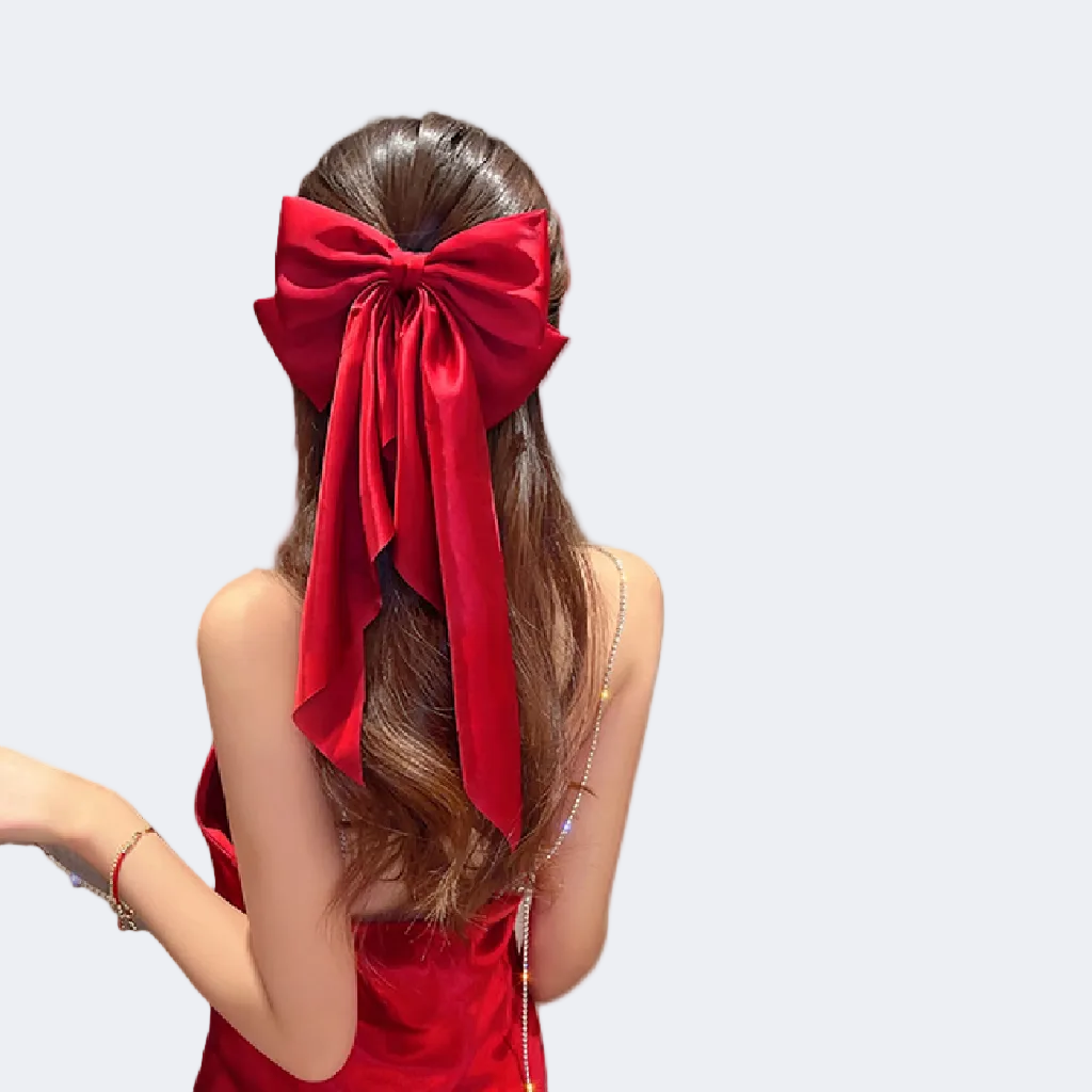 Person with long dark hair wearing a large red bow in the back on a white background