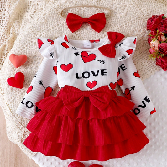 Children's outfit with red and white dress and matching headband on a textured surface.