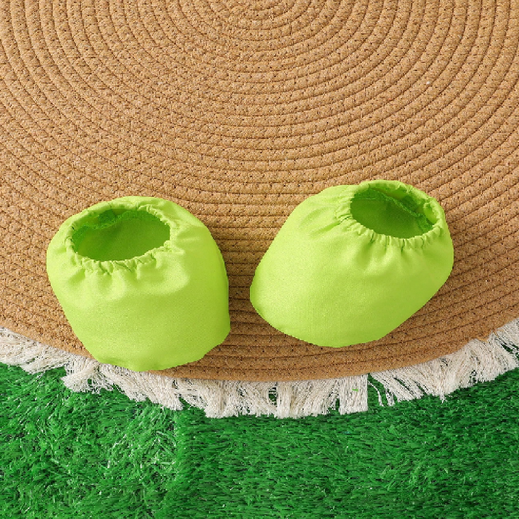 Two bright green baby shoes on a straw hat with a grassy background