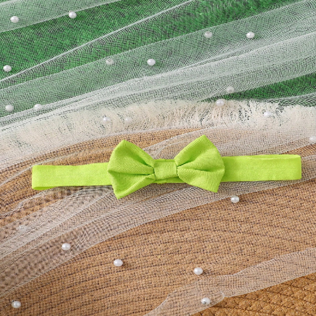 Green bow tie on a textured fabric background