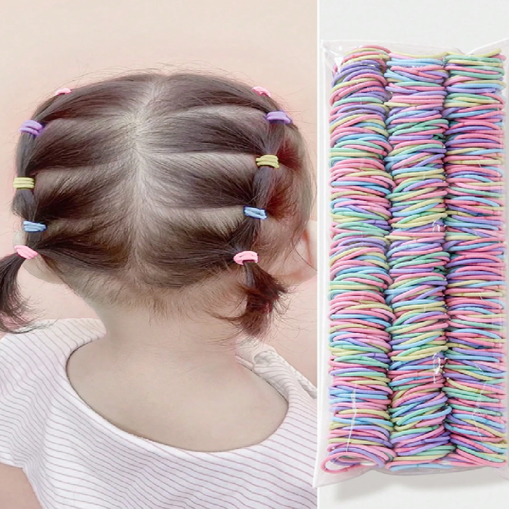 Child with braided hair using colorful hair ties and a large stack of similar hair ties on a beige background.