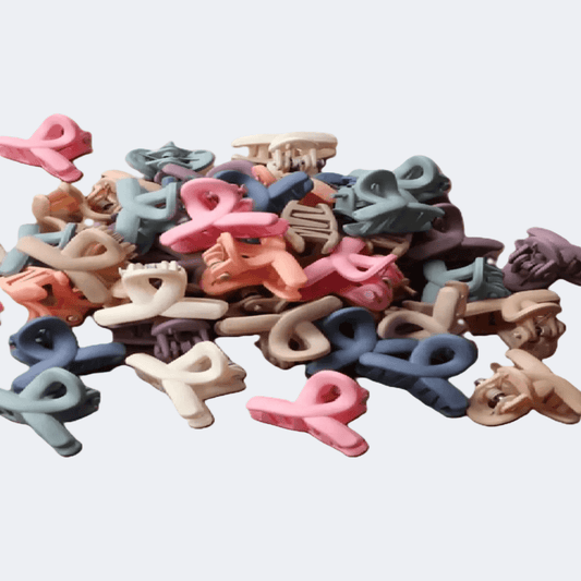 Assorted colorful letter-shaped hair clips on a light gray background