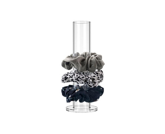 Set of hair scrunchies in gray, black, and white patterned designs on a clear cylindrical stand 