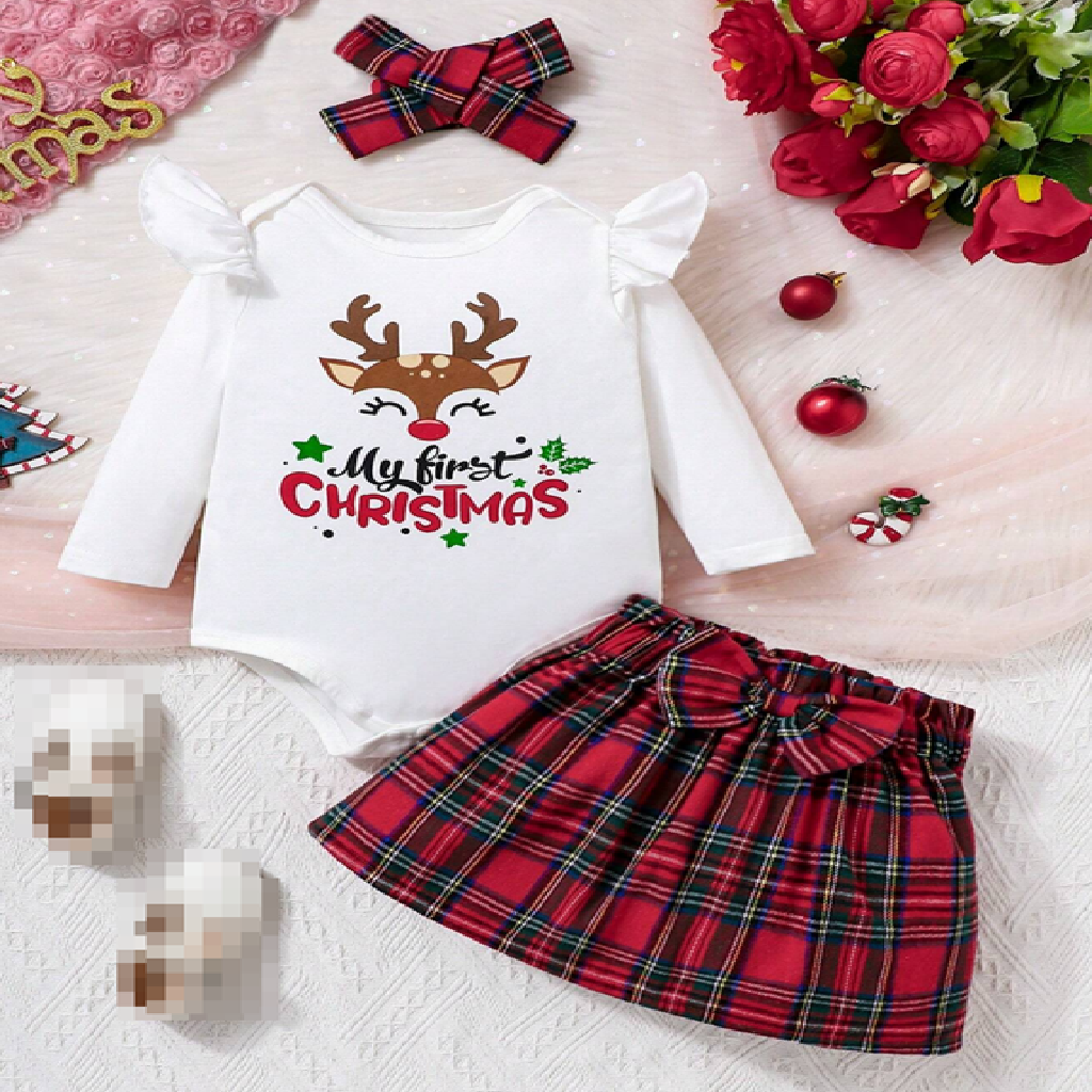 Christmas-themed baby outfit with red plaid skirt and white top with reindeer design on a light background.