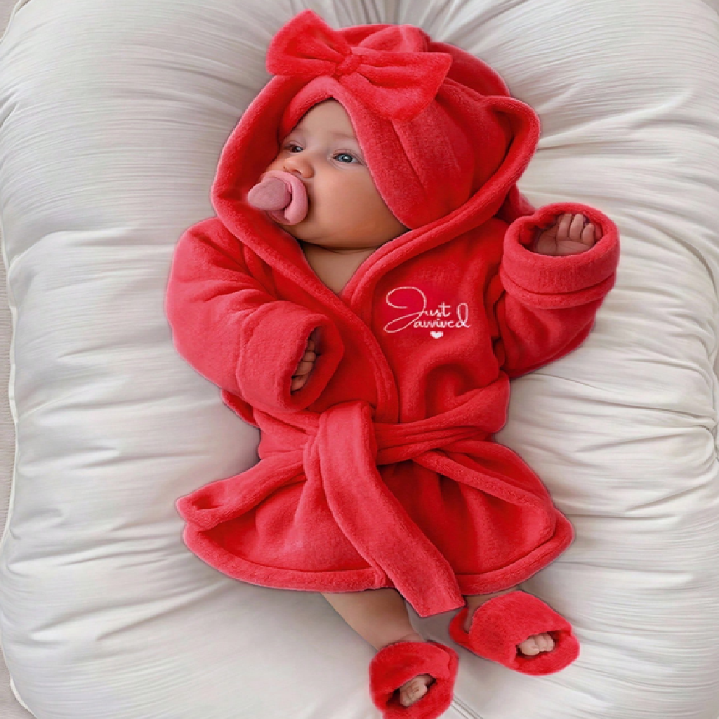 Baby in a red hooded outfit with a bow on a white background