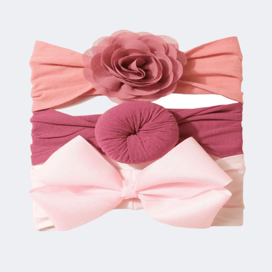 Set of three colorful headbands with floral and bow designs on a light gray background