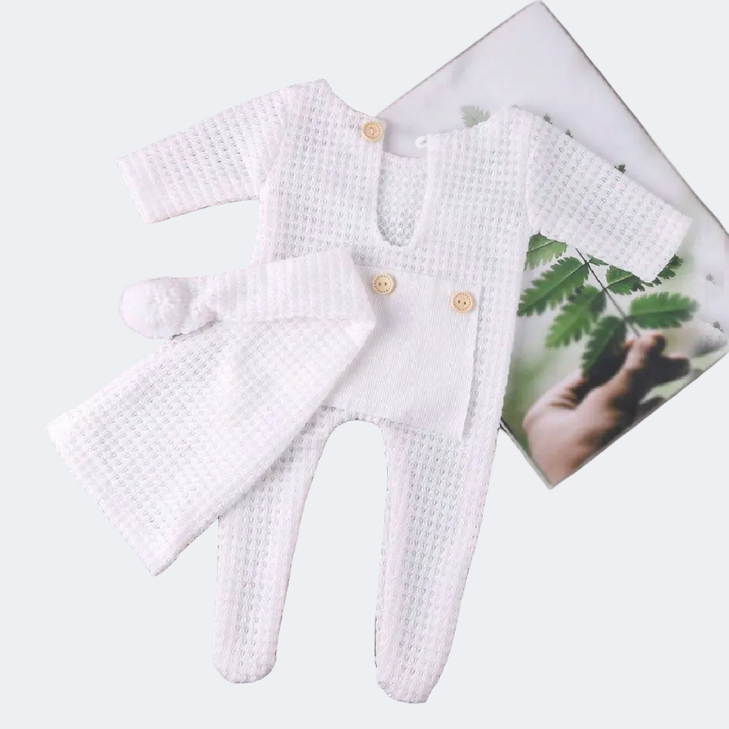 White baby outfit with buttons on a wooden surface