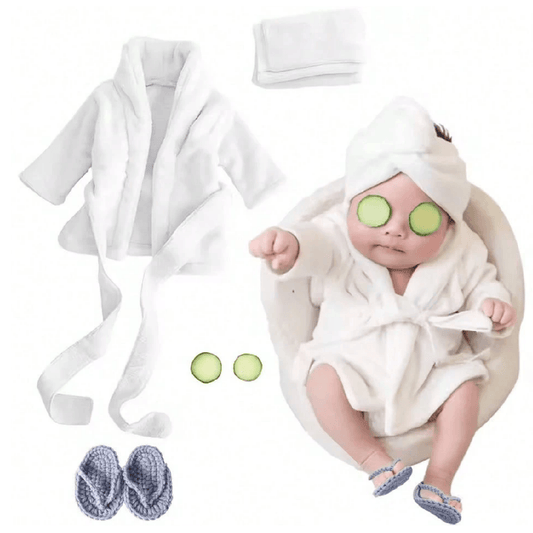 Baby in a white robe with cucumber slices on eyes, surrounded by bath accessories on a white background