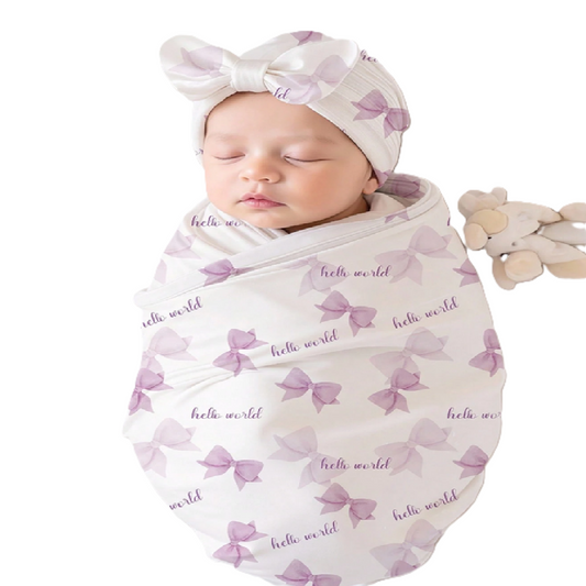 Newborn baby wrapped in a 'hello world' swaddle with a matching headband 