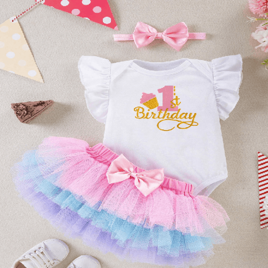 Baby outfit with '1st Birthday' design, colorful tutu, and headband on a neutral background.