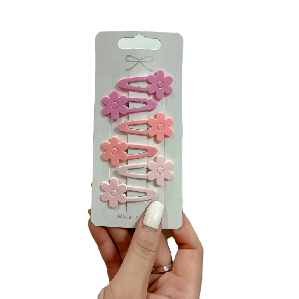 Packaged pink flower-shaped clips held by a hand on a white background