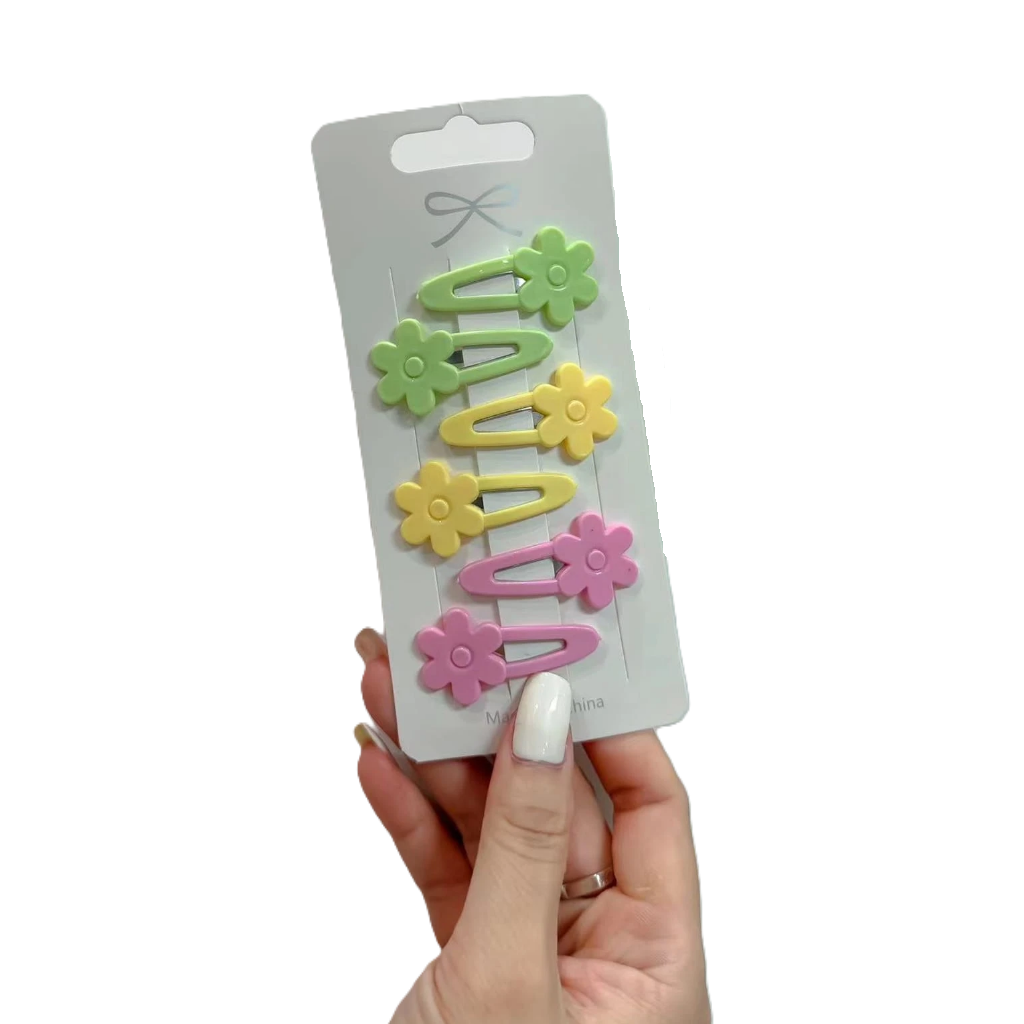 Set of colorful flower-shaped clips on a branded card held by a hand against a white background