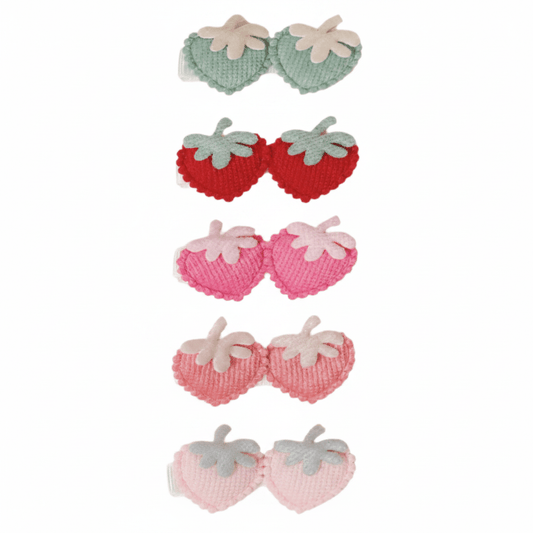 Set of strawberry-shaped hair clips in red, pink, and green on a white background