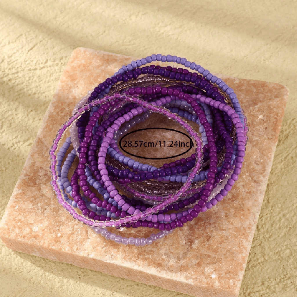Stack of purple beaded bracelets on a stone surface