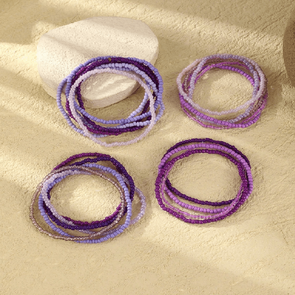 Set of purple beaded bracelets on a beige surface