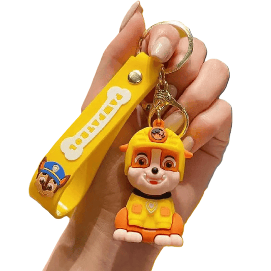 Hand holding a yellow nail clipper with a cartoon character keychain on a white background
