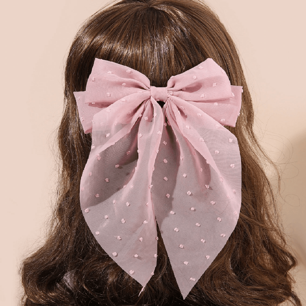 Pink bow-shaped fabric with polka dots on a beige surface