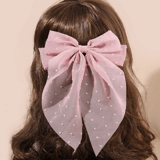 Pink bow-shaped fabric with polka dots on a beige surface