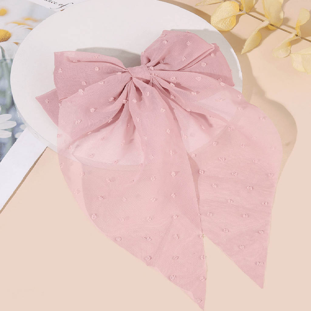 Pink bow-shaped fabric with polka dots on a beige surface