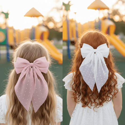 Woman with long blonde hair wearing a large white and Pink polka dot bow in her hair, against a plain background.