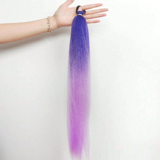 Purple hair extension held by a hand on a white background