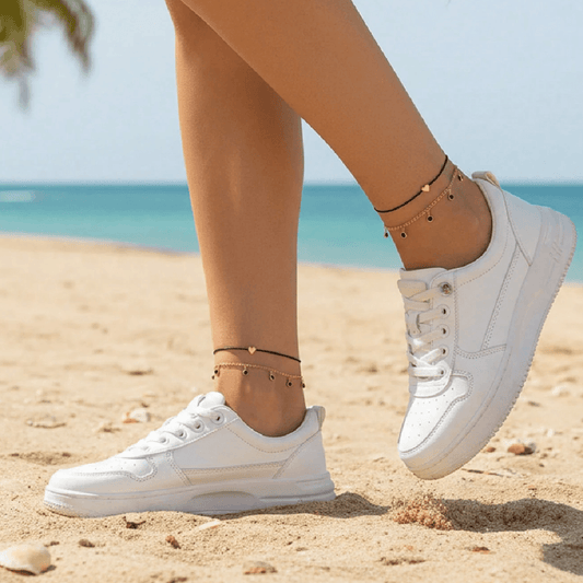 White sneakers on a sandy beach with ocean in the background