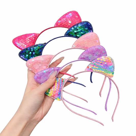 Colorful sequin cat ear headbands held by a hand on a white background