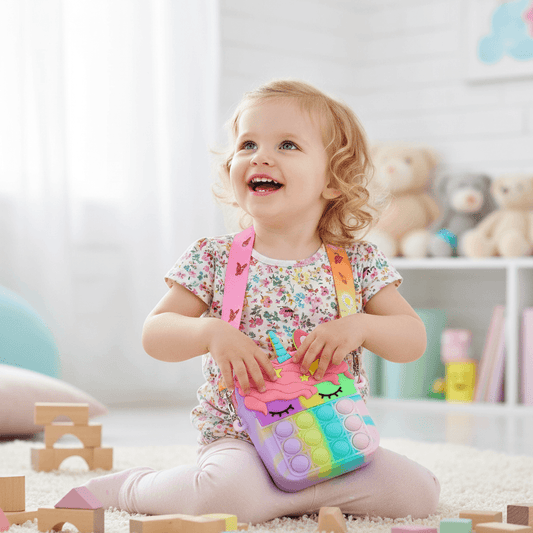 Colorful unicorn-themed pop-it fidget toy with a keychain on a white surface.