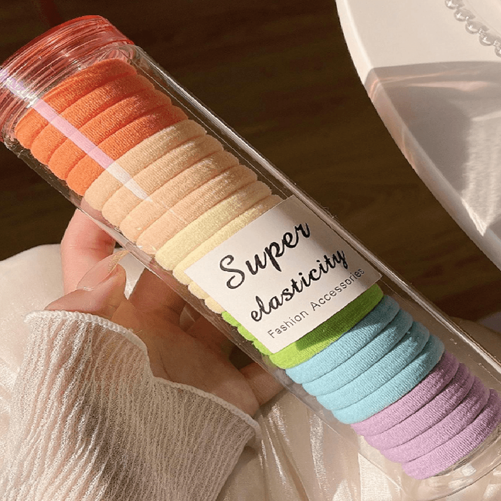 Set of colorful hair ties in a box labeled 'Super elasticity' held by a person.
