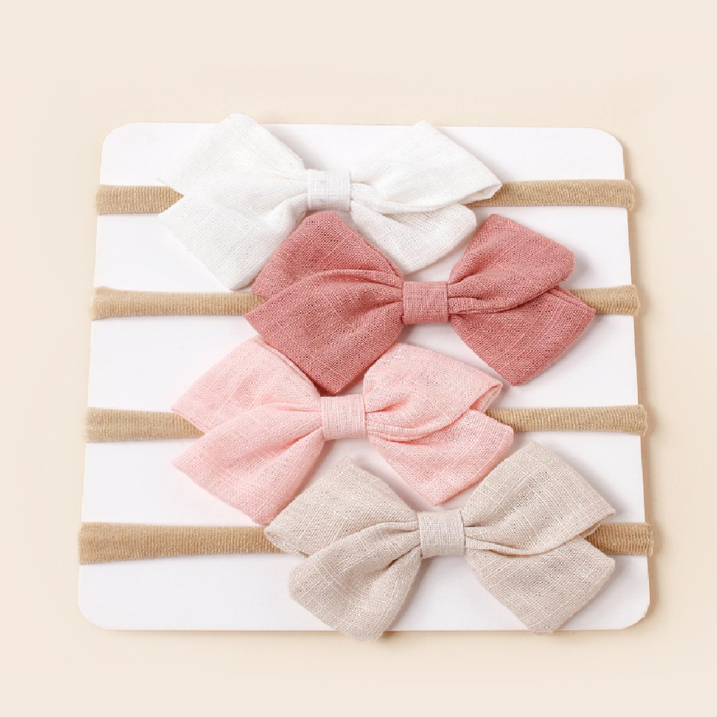 Set of four fabric bows in pink, beige, and white on a striped background